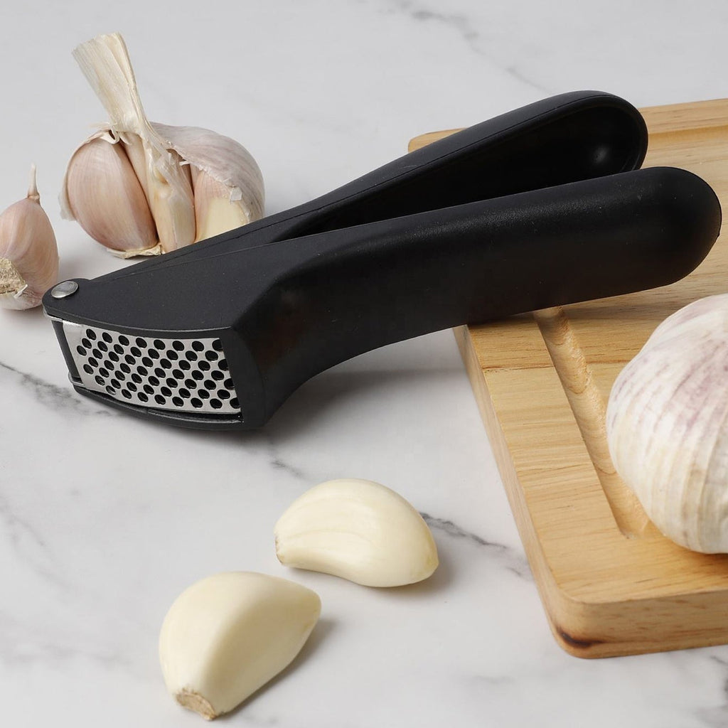 Manual garlic press crusher tool placed in modern kitchen setting