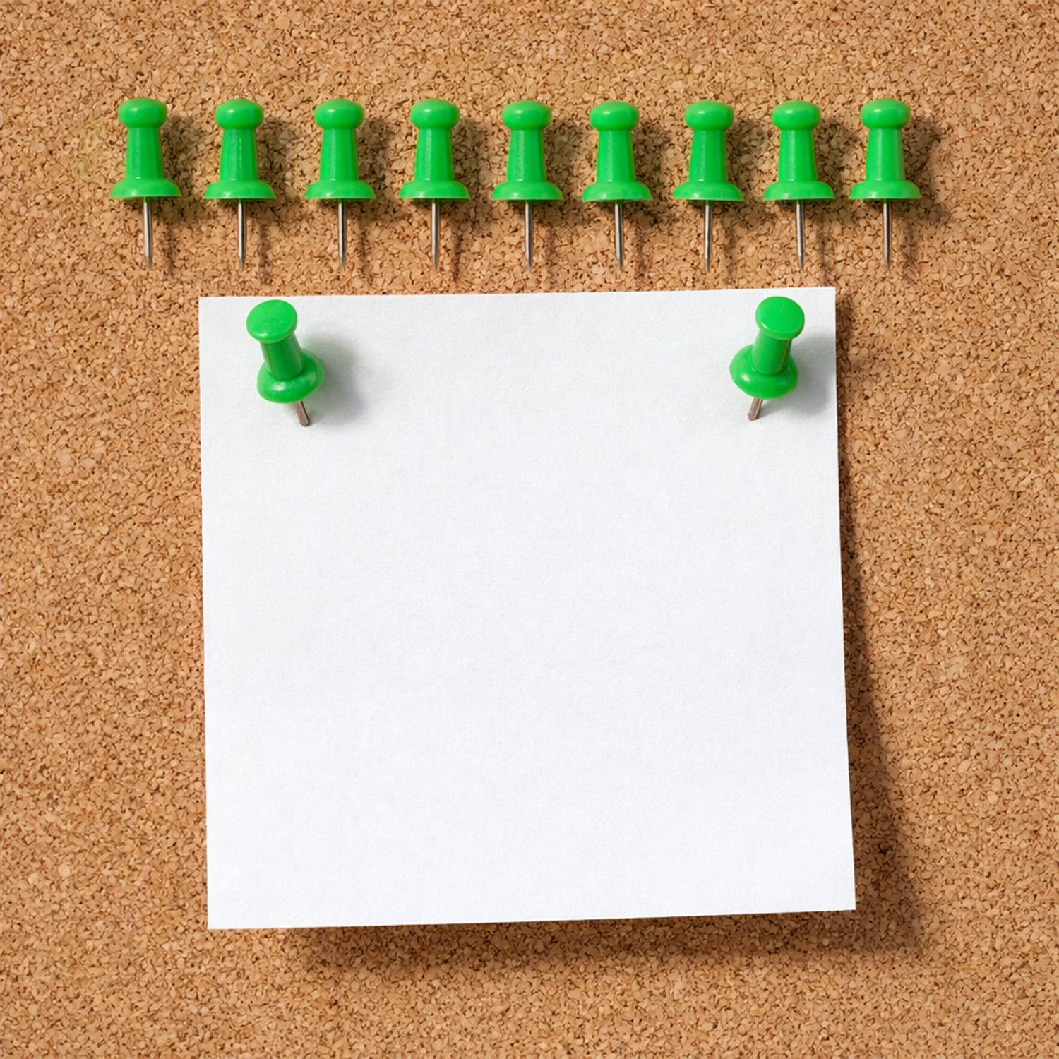 Green push pin fixing paper on a cork notice board