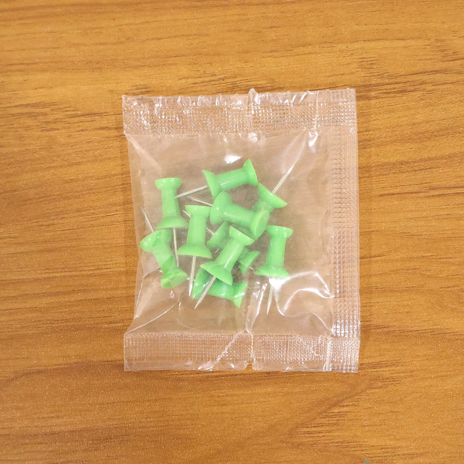 Multiple green push pins arranged showing sharp metal pins