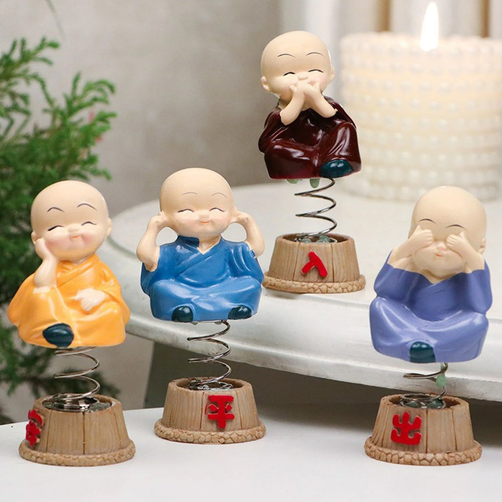 Baby monk figurines displayed on a car dashboard
