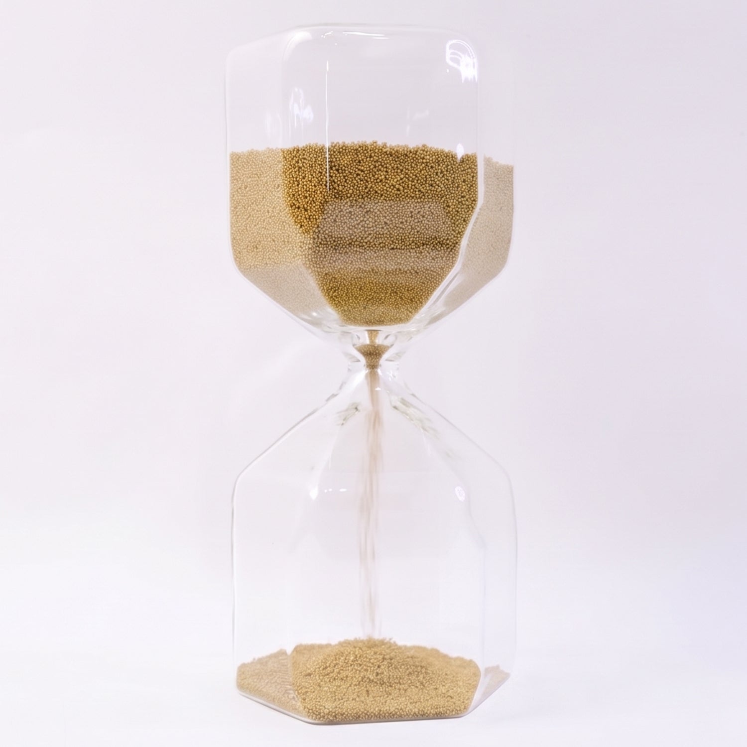 Close-up of yellow sand flowing smoothly in a glass hourglass timer.