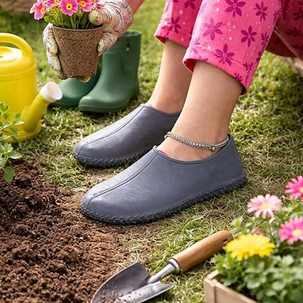 A person wears grey silicone shoe covers while gardening, surrounded by soil, plants, and a watering can.