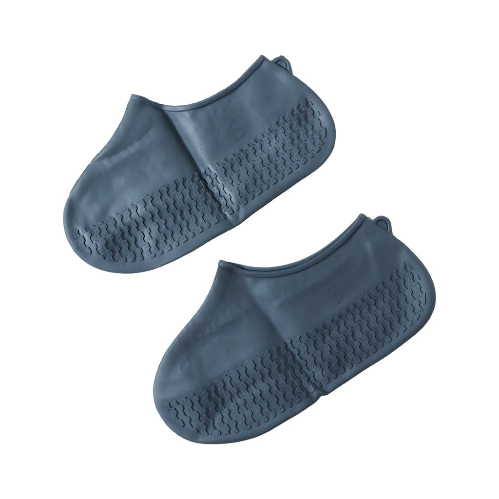A pair of dark gray silicone shoe covers with textured soles is displayed against a plain white background.